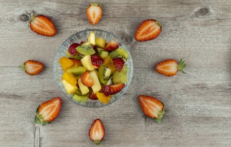 fruit salad in a glass plate and strawberry berries. flat layout, copy space. richest source of...