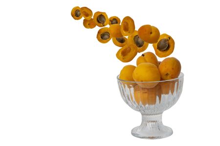flying fruit apricots isolated on a white background. juicy fruit falls into a glass bowl. selective focusの写真素材