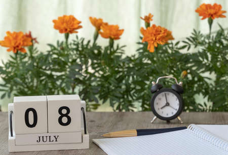 July 08, date on the calendar. Handmade wood cube with date month and day. flowers and clocks are in...