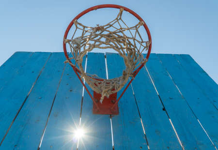 old basketball shield with a ring on the sky background. sun shines through the cracks between the...