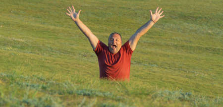 man spread his arms wide, rejoicing in nature. man on green hills, photographed from the waist upの写真素材