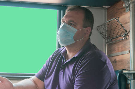 man in a medical mask near the train car. concept of travel during the pandemic. mode of permanent...