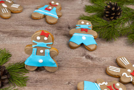 gingerbread man in a medical mask. cookies made with your own hands on a wooden surface. treats for new year's holidays and Christmasの写真素材