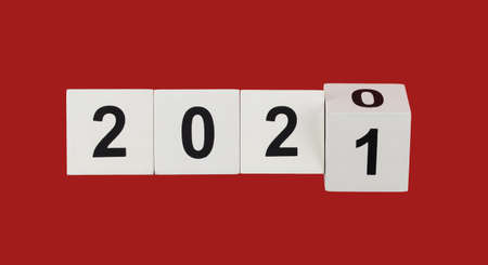 white wooden cubes with black numbers 2021 on a red background. happy xmas. numbers symbolize the...