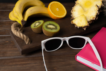 sunglasses and fruit on the table. the concept of a holiday in tropical countries. exotic fruits on vacation. summer moodの写真素材