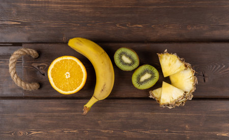tropical fruits on a wooden background. fresh banana and kiwi. sliced orange and pineapple. dietary nutrition, the use of vitamins. healthy lifestyle. upper view, copy spaceの写真素材