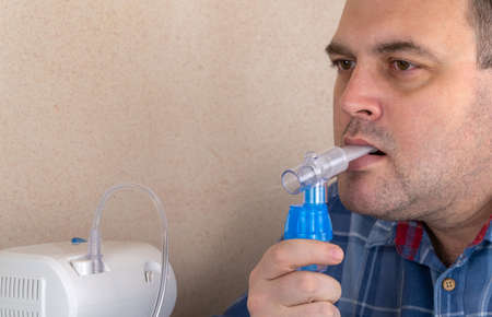 man makes inhalations with the help of nebulizer. patient breathes through an Oxygen Mask. device for nebulization of a medicinal substance. used in the treatment of bronchial asthma and respiratoryの写真素材