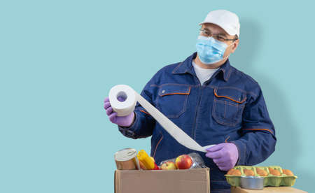 Delivery man puts products in a paper bag and carton box. selective focus. volunteer is wearing...