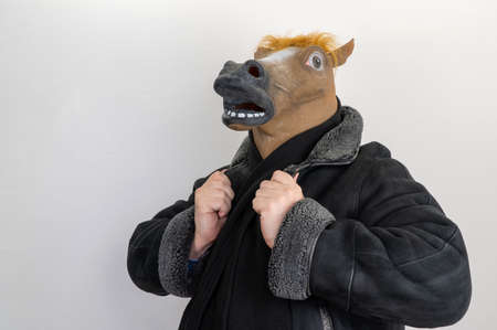 man in a horse mask. selective focus. horse is wearing a coat. male stud.の写真素材