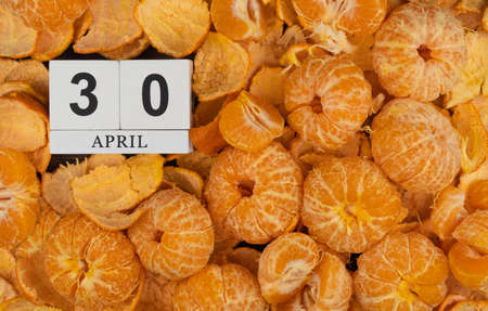 April 30, date on the calendar. Handmade wood cube with date month and day. calendar is littered...