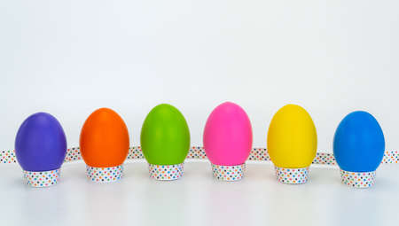 colorful eggs tied with a festive ribbon on a white wooden background.の写真素材