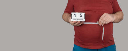 fat man measures the size of the abdomen with a centimeter measuring tape. September 15, Losing Weight Day. people suffer from excess weight. banner, copy spaceの写真素材