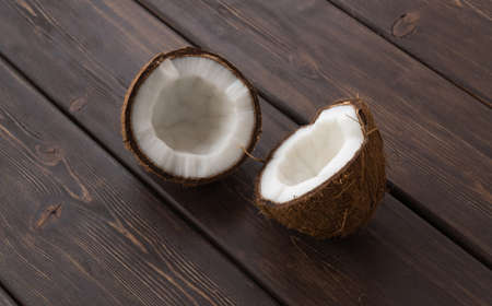 split coconut on wooden planks. Coco, ripe palm fruit. outside of the fruit is covered with a...
