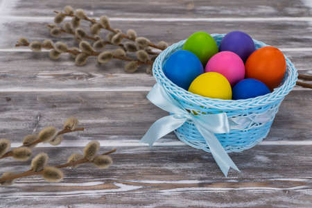 festive basket with painted Easter eggs on a creative wooden background. decorated with pussy willow. palm sundayの写真素材
