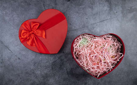 red box in the shape of a heart on a dark background. festive packaging for romantic gifts. upper view, copy space. celebration of International Womens Day and Valentines Day.の写真素材