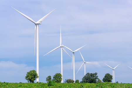 Wind turbine on the green meadow over the blue clouded skyの写真素材