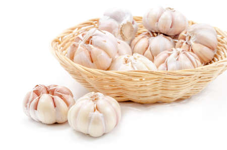 Fresh organic garlic in bamboo basket on white backgroundの写真素材