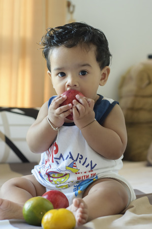 a healthy boy are sitting and eating an apple on bedの写真素材