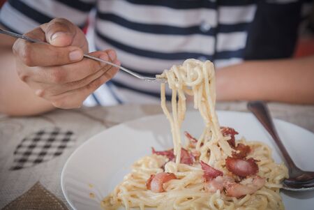 spaghetti bolognese roll up on the fork with young woman hand in food shop.の写真素材