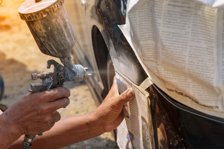 automobile repairman painter hand  with airbrush pulverizer painting car body in paint chamberの写真素材