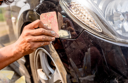 mechanic worker repairman fixing scratched on car body and preparing for painting.の写真素材