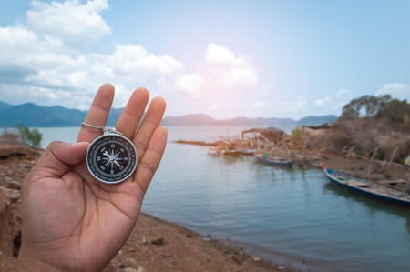Left hand holding the magnetic compass shows the directions north, south, east, and west on the compass faceの写真素材