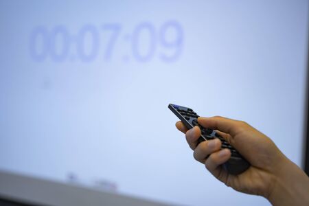 A remote controller with right hand behind the white board at the office
