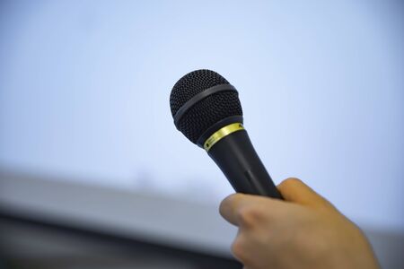 A microphone with left hand behind the white board at the officeの写真素材
