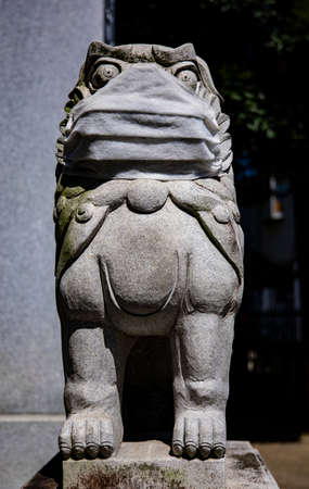 A statue of Guardian dog wearing mask at Meguro fudo temple in Tokyoの写真素材