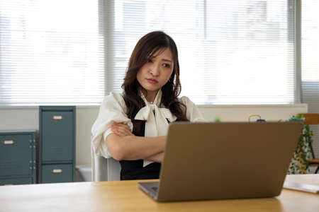 A worried Japanese woman by remote work in the small officeの写真素材