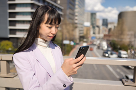 A portrait of Japanese woman using smartphone behind cherry blossomの写真素材