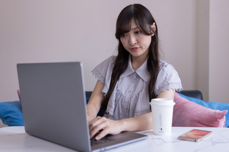 A Japanese woman working by laptop in the living room