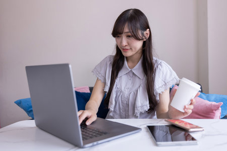 A Japanese woman working by laptop in the living room