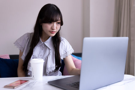 A Japanese woman working by laptop in the living room