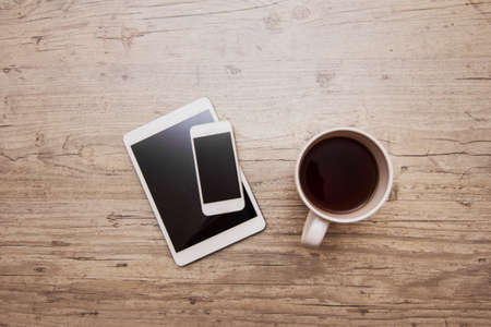 cup of coffee, smart phone and tablet on gray wooden backgroundの写真素材