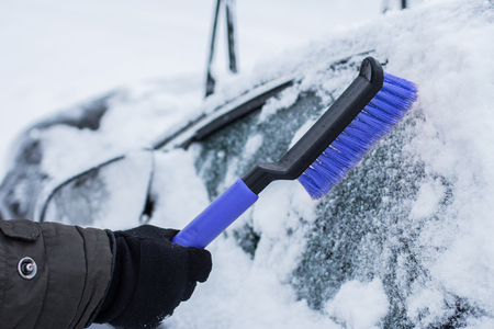 car, winter, people and vehicle concept - closeup of man pushing car stuck in snowの写真素材