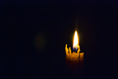 Candle burns on a black backgroundの写真素材