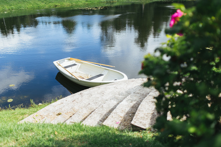 Boat with oars on the stone ancient stairs on the shore of a small lake