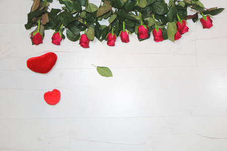 Red roses on wooden background. Nearby is a red heart.の写真素材