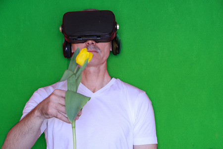 Close-up - a man with glasses of virtual reality gives a yellow tulip of virtual love