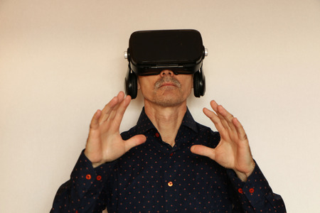 Close-up of a man in a black T-shirt with glasses of virtual reality. The background is white.