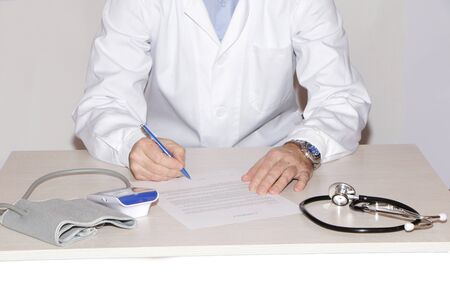 The doctor signs a contract with the patient. On the table is a medical instrument a stethoscope, a...