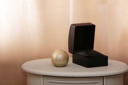 Black gift box for jewelry on a white table. Pink background.