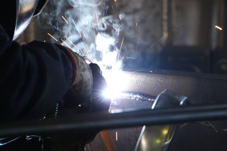 A highly skilled welder welds a metal structure at an assembly plant. Welding process 135.