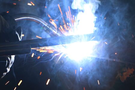 A highly skilled welder welds a metal structure at an assembly plant. Welding process 135.