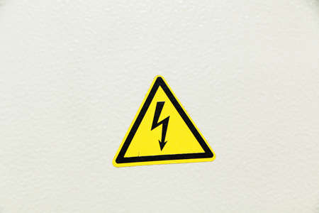 A danger sign in the form of a black arrow on an electrical panel. The background is white.