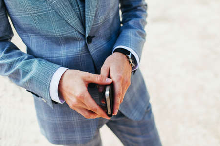 Modern businessman. A confident young man in a full suit with a smartphone in his hand and an expensive watch.の写真素材