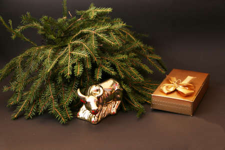 Bull as a symbol of New Year and Christmas 2021 on a black background of a Christmas tree and decor. Metal bull on the background of a green Christmas tree and gifts.の写真素材