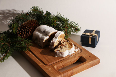 A beautiful Christmas cake, decorated with fir branches with a pine cone and a gift box, on a wooden...