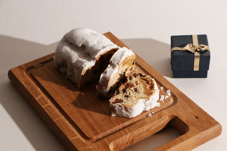 Beautiful birthday cake with a gift box, on a wooden board. View from above. The background is...